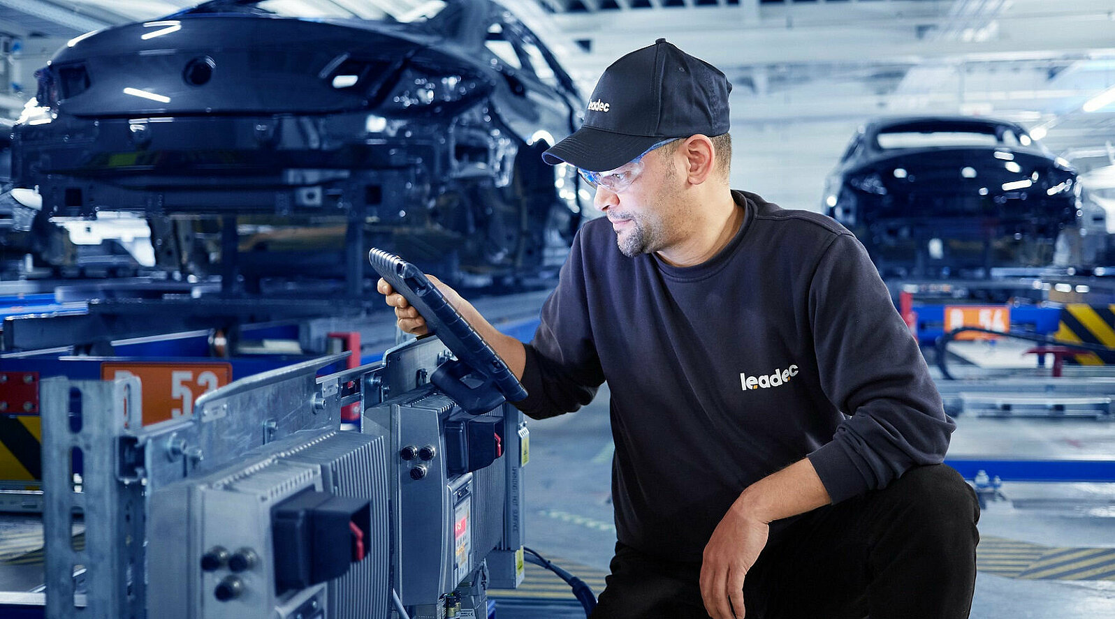 A Leadec employee configures an inverter at a conveyor belt.