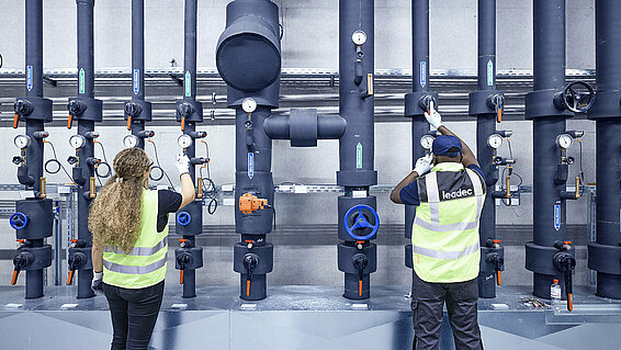 Leadec employees inspecting pipes of refrigeration supply system.
