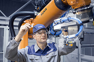 A Leadec employee maintaining a robot in a production.